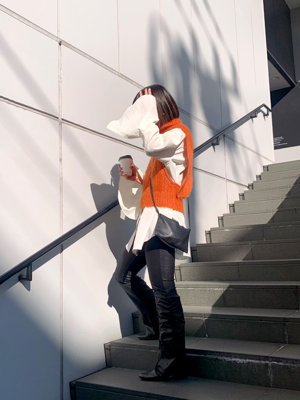 ブラック系のその他パンツ、オレンジ系のベスト、ホワイト系のシャツ/ブラウスを着用したレディースの冬コーディネートの2枚目の写真