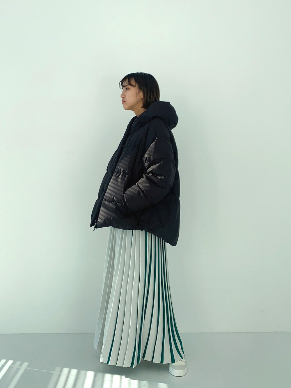 ブラック系のダウンジャケット/コート、ホワイト系のスカートを着用したレディースの冬コーディネートの2枚目の写真