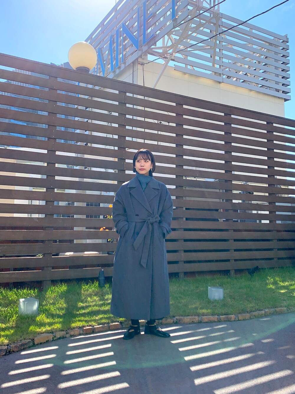 グレー系のチェスターコート、グレー系のニット/セーターを着用したレディースの秋コーディネートの3枚目の写真