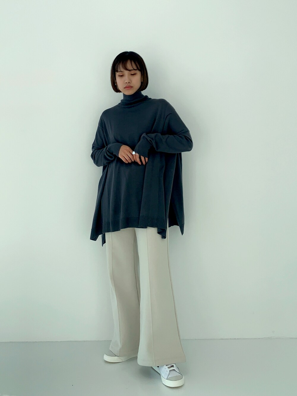 グレー系のニット/セーター、ホワイト系のスウェットパンツを着用したレディースの秋コーディネートの2枚目の写真