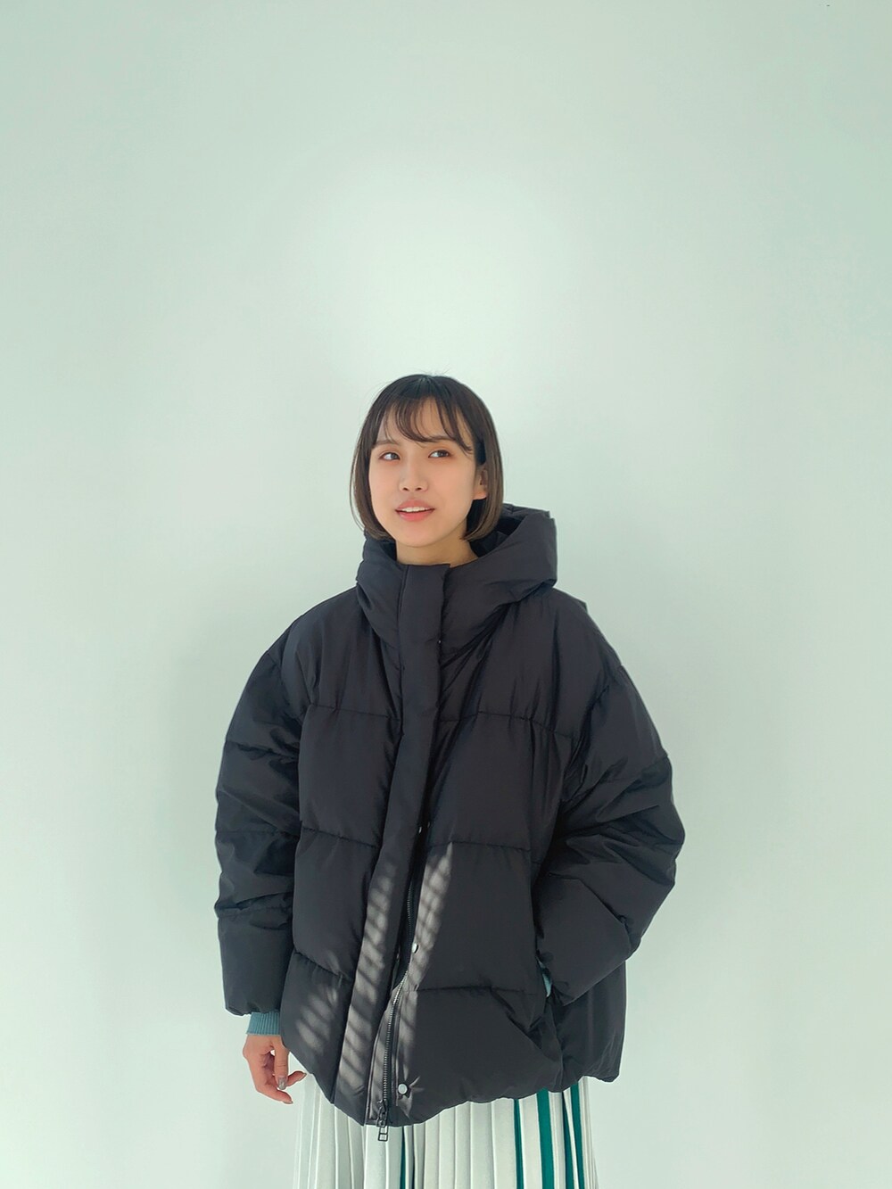 ブラック系のダウンジャケット/コート、ホワイト系のスカートを着用したレディースの冬コーディネートの3枚目の写真