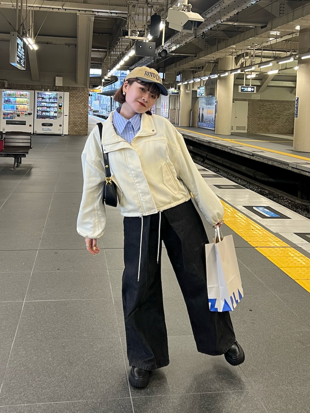 ブラック系のデニムパンツ、ブラック系のローファー、ブラック系のショルダーバッグを着用したレディースの春コーディネートの2枚目の写真