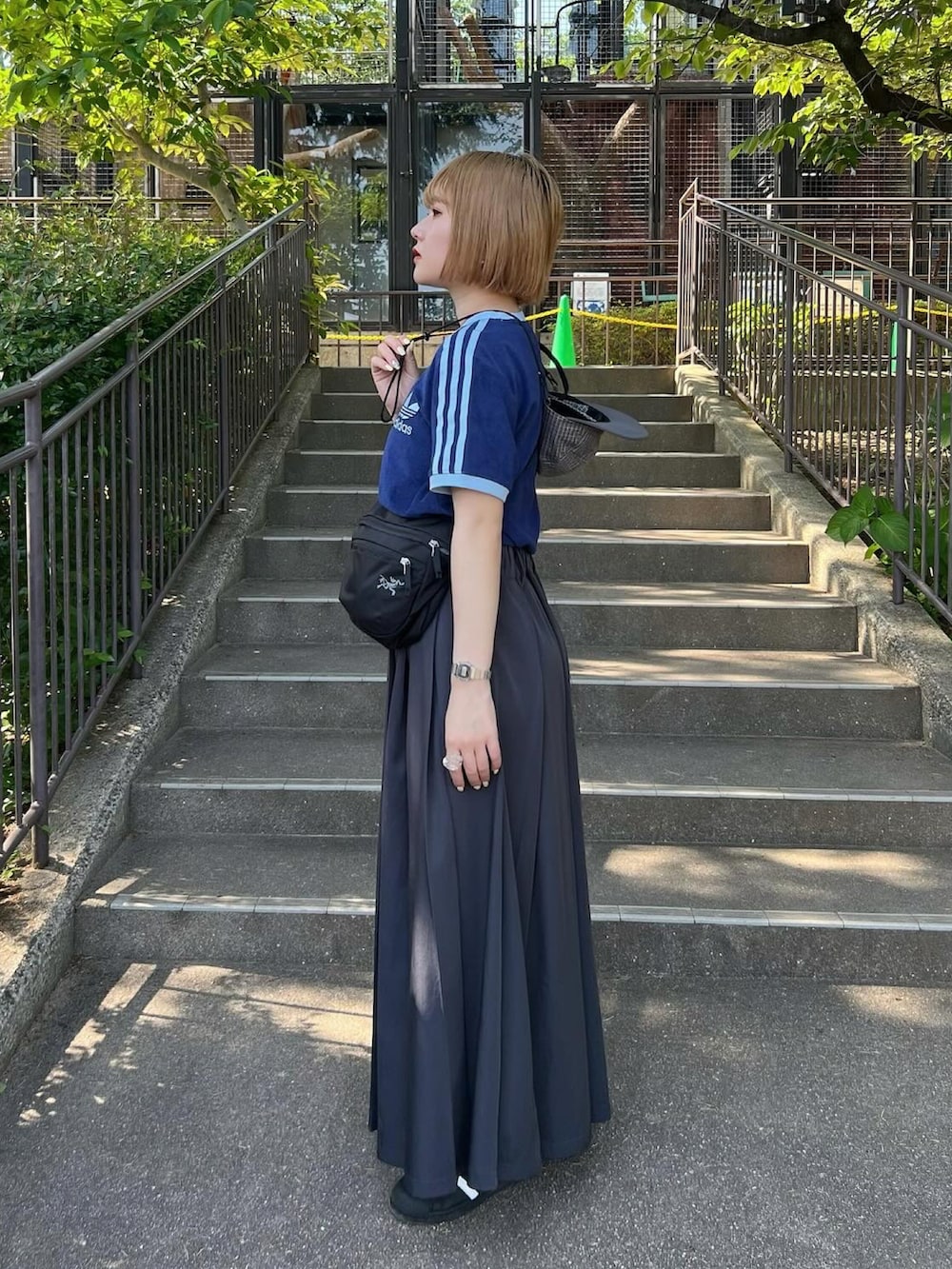 ブルー系のTシャツ/カットソー、グレー系のスカート、ブラック系のスニーカーを着用したレディースの春コーディネートの2枚目の写真