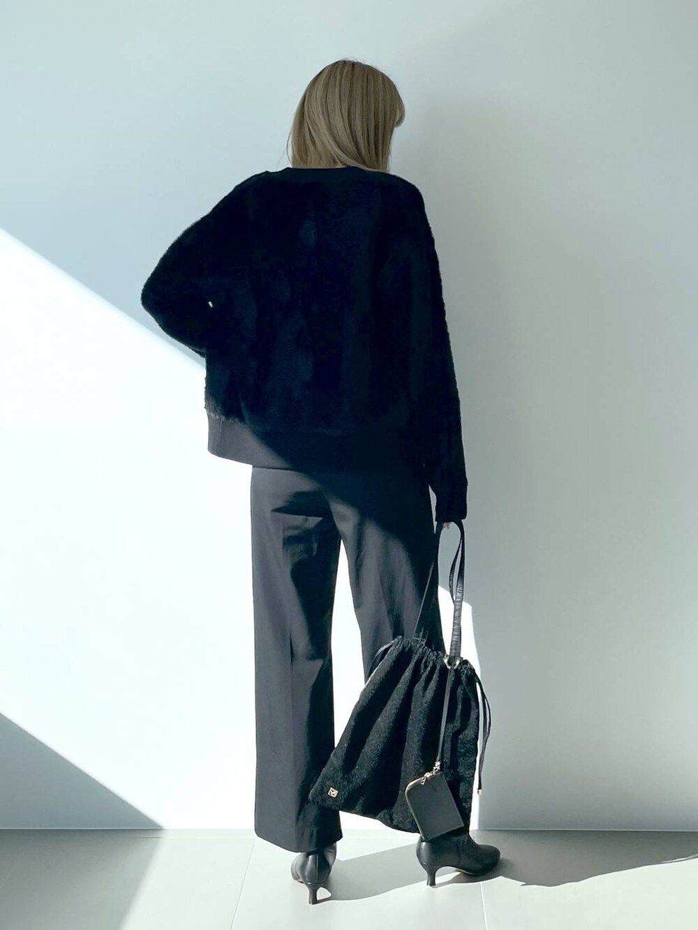 ブラック系のタンクトップ、ブラック系のブーツ、ブラック系のトートバッグを着用したレディースの冬コーディネートの3枚目の写真