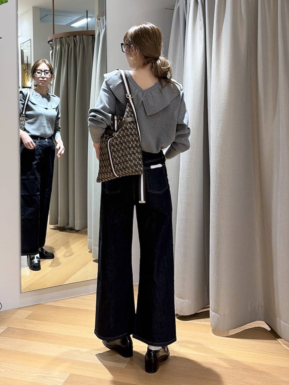 ブルー系のデニムパンツ、ブラウン系のショルダーバッグ、グレー系のニット/セーターを着用したレディースの冬コーディネートの3枚目の写真