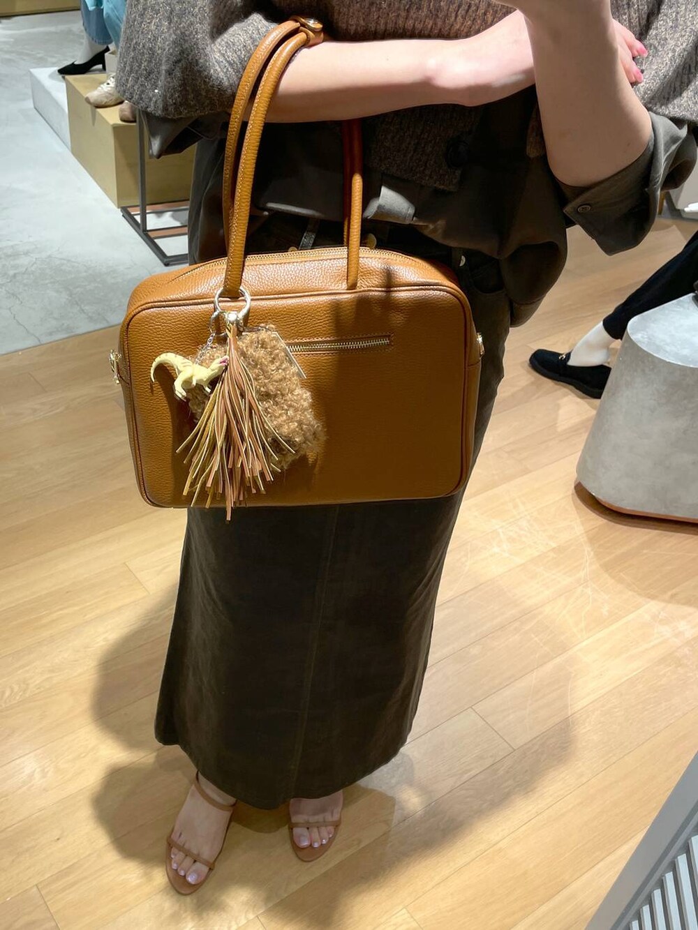 ブラウン系のサンダル、ベージュ系のニット/セーター、グリーン系のスカートを着用したレディースの秋コーディネートの2枚目の写真