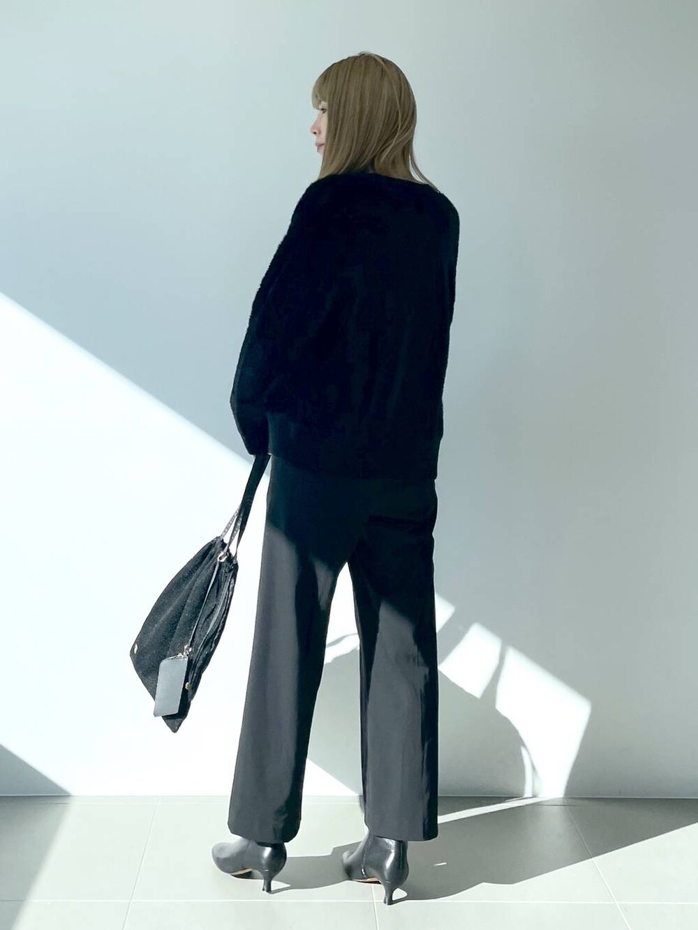 ブラック系のタンクトップ、ブラック系のブーツ、ブラック系のトートバッグを着用したレディースの冬コーディネートの2枚目の写真