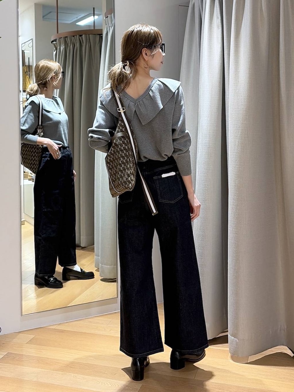 ブルー系のデニムパンツ、ブラウン系のショルダーバッグ、グレー系のニット/セーターを着用したレディースの冬コーディネートの4枚目の写真