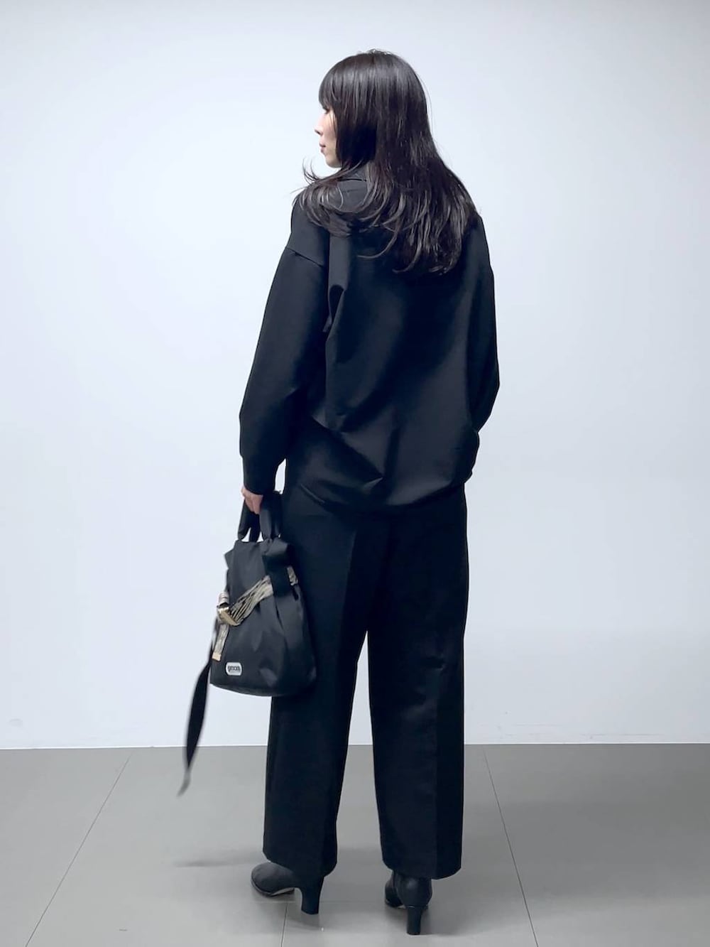 ブラック系のブーツ、ブラック系のシャツ/ブラウス、ブラック系のスラックスを着用したレディースの秋コーディネートの2枚目の写真