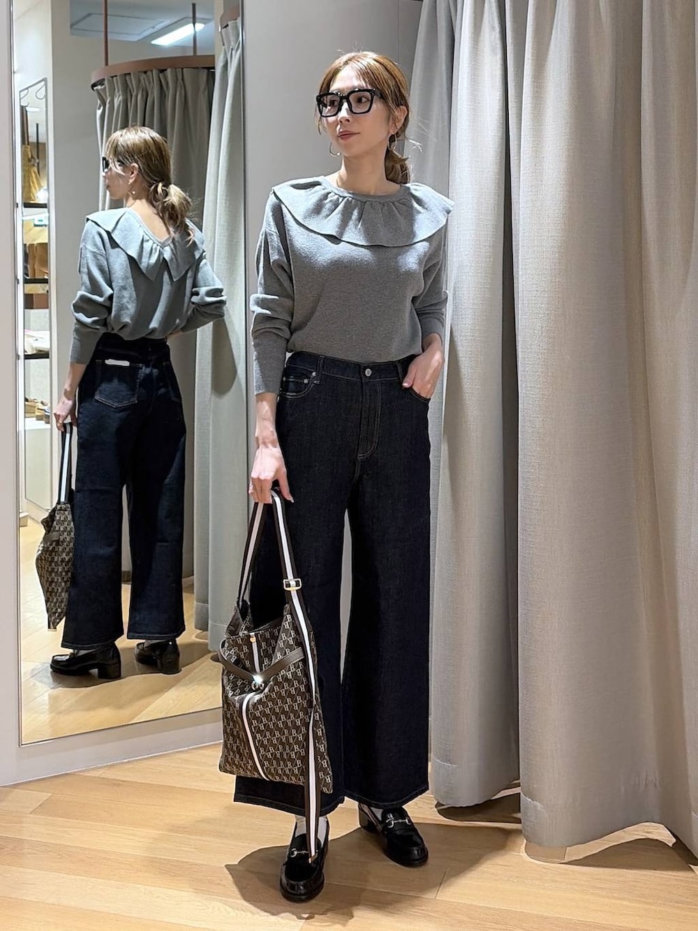 ブルー系のデニムパンツ、ブラウン系のショルダーバッグ、グレー系のニット/セーターを着用したレディースの冬コーディネートの2枚目の写真