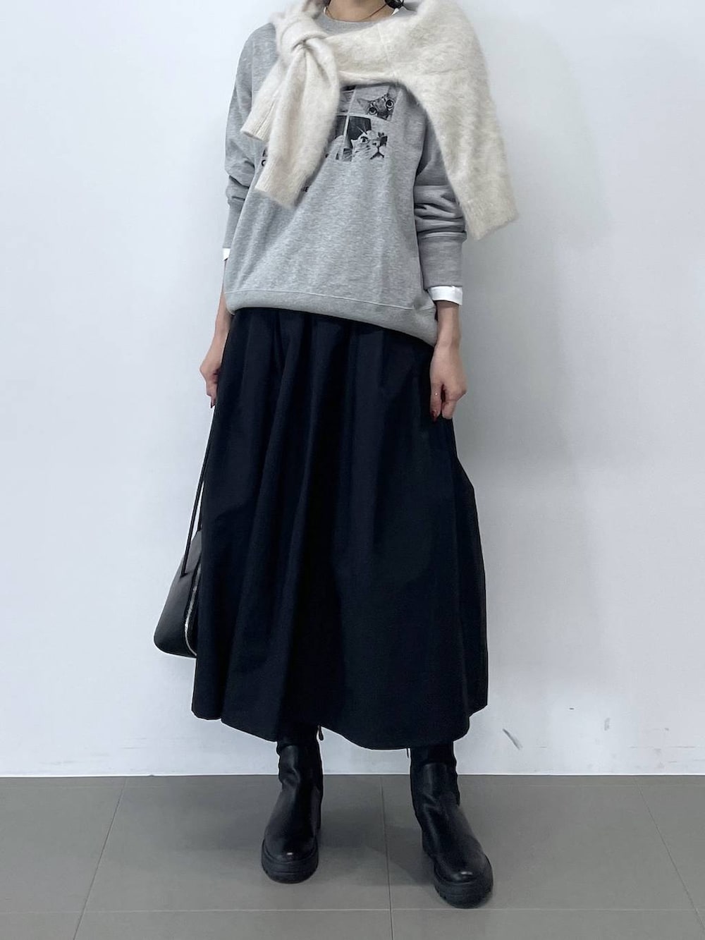 ブラック系のトートバッグ、ブラック系のブーツ、ホワイト系のTシャツ/カットソーを着用したレディースの秋コーディネートの2枚目の写真