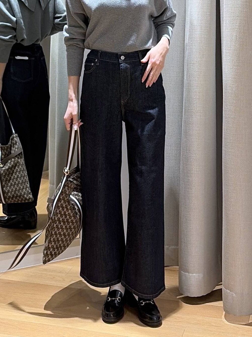 ブルー系のデニムパンツ、ブラウン系のショルダーバッグ、グレー系のニット/セーターを着用したレディースの冬コーディネートの7枚目の写真