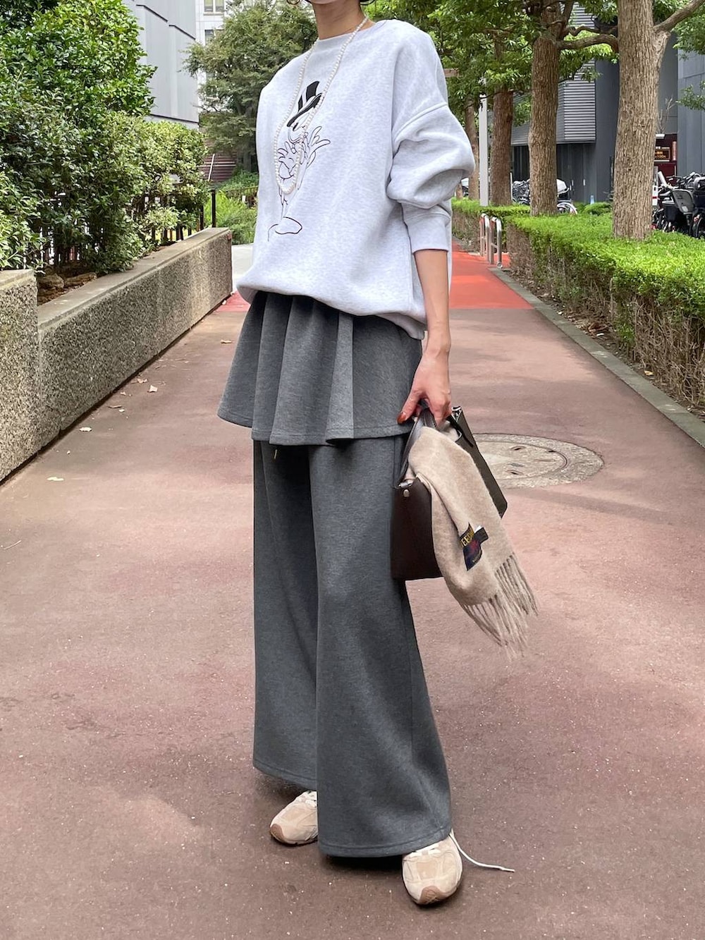 ベージュ系のスニーカー、グレー系のスウェットパンツ、グレー系のスカートを着用したレディースの秋コーディネートの4枚目の写真