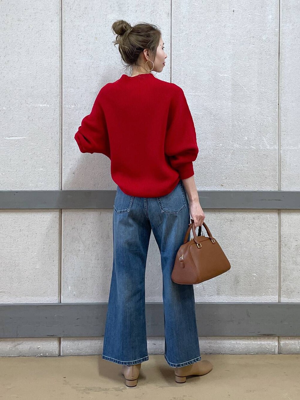 イエロー系のボストンバッグ、ベージュ系のブーツ、ブルー系のデニムパンツを着用したレディースの冬コーディネートの2枚目の写真