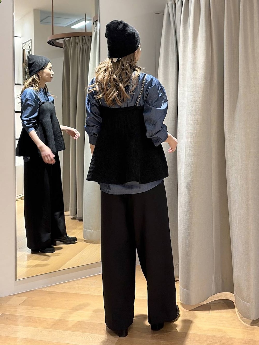 ブルー系のシャツ/ブラウス、ブラック系のニット/セーター、ブラック系のスラックスを着用したレディースの秋コーディネートの2枚目の写真