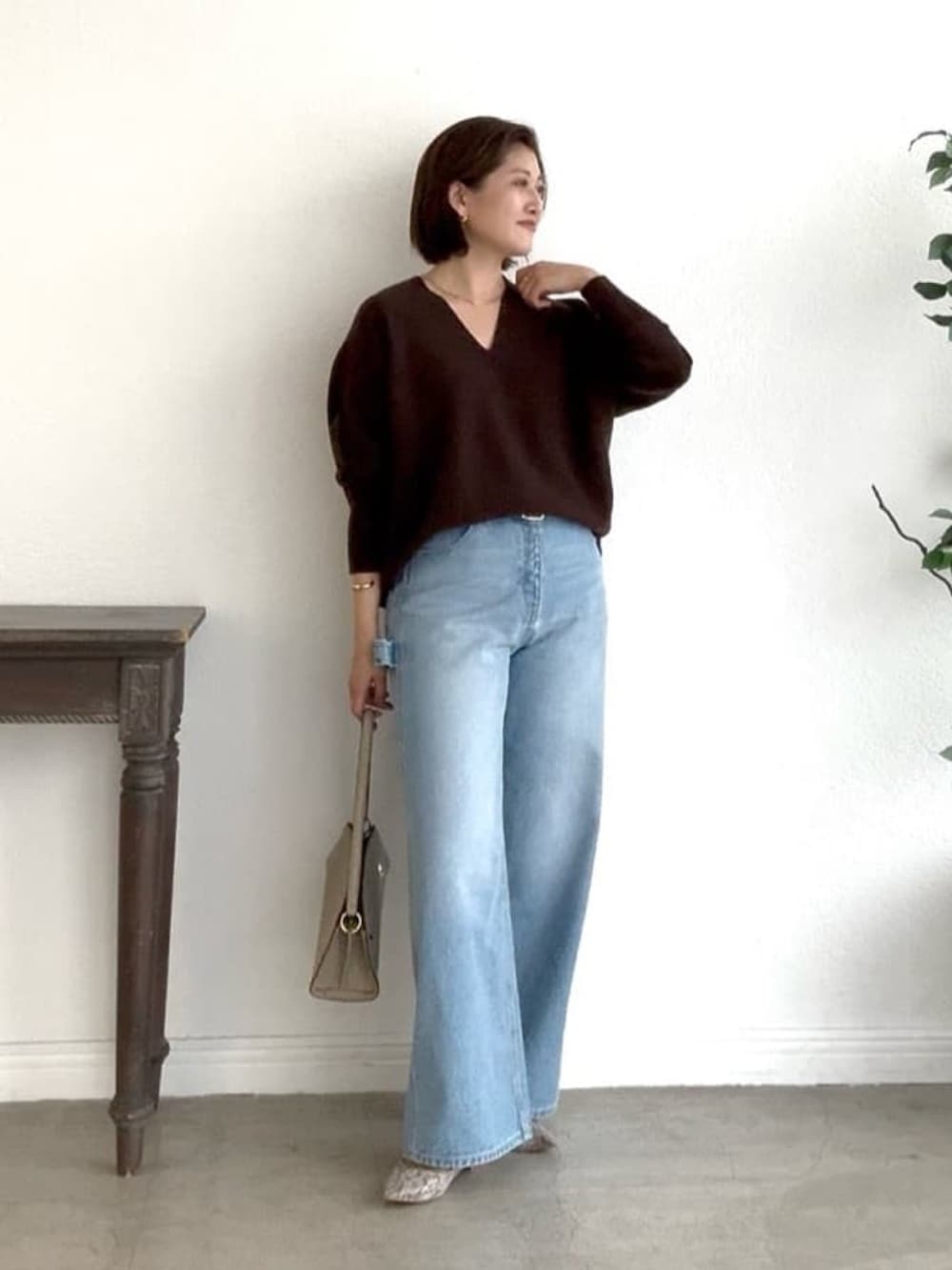 ブラウン系のニット/セーター、ブルー系のデニムパンツ、ベージュ系のハンドバッグを着用したレディースの秋コーディネートの2枚目の写真
