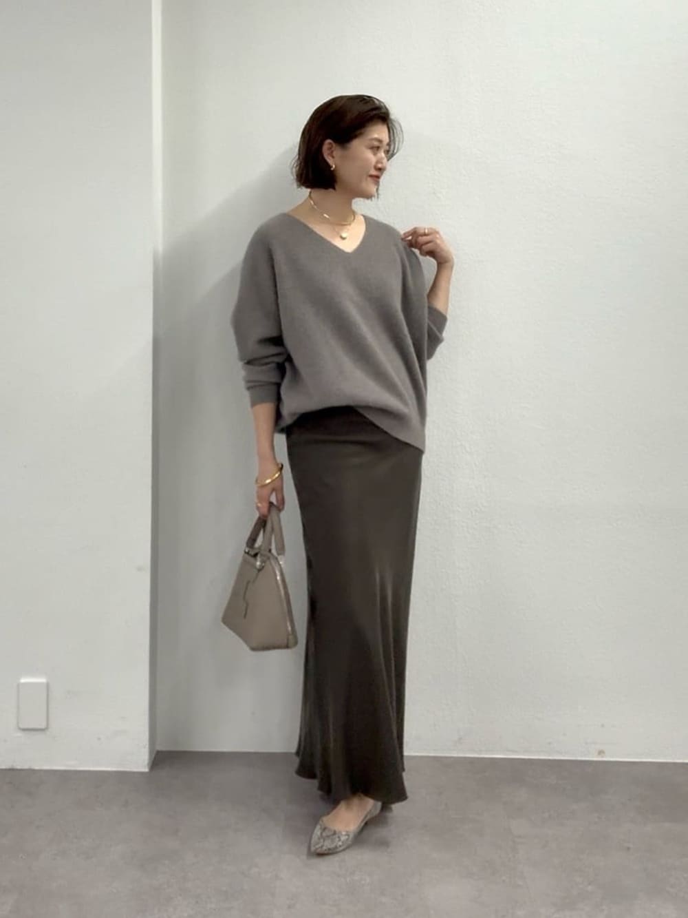 グレー系のニット/セーター、ブラウン系のスカート、グレー系のパンプスを着用したレディースの冬コーディネートの3枚目の写真