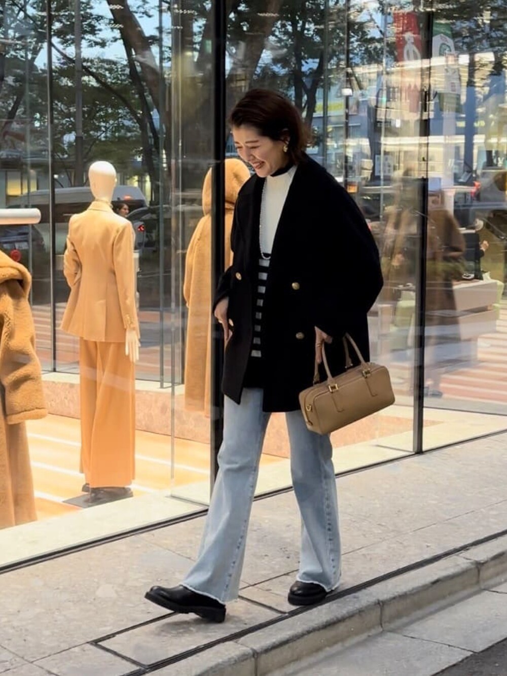 ブルー系のデニムパンツ、イエロー系のボストンバッグ、ブラック系のブーツを着用したレディースの秋コーディネートの2枚目の写真