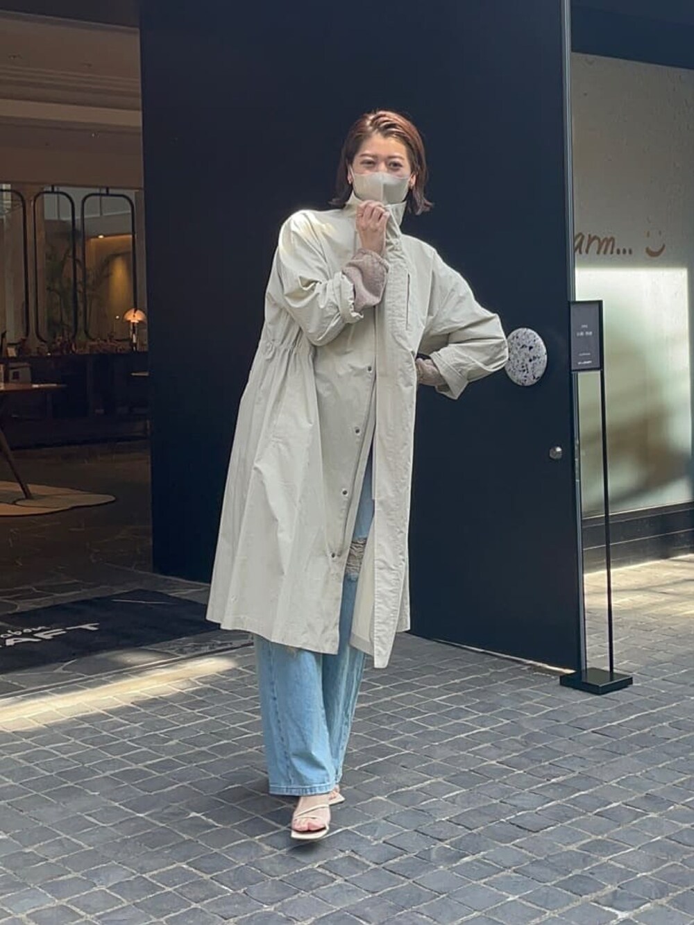 グリーン系のモッズコート、ブラック系のニット/セーター、ブルー系のデニムパンツを着用したレディースの春コーディネートの4枚目の写真