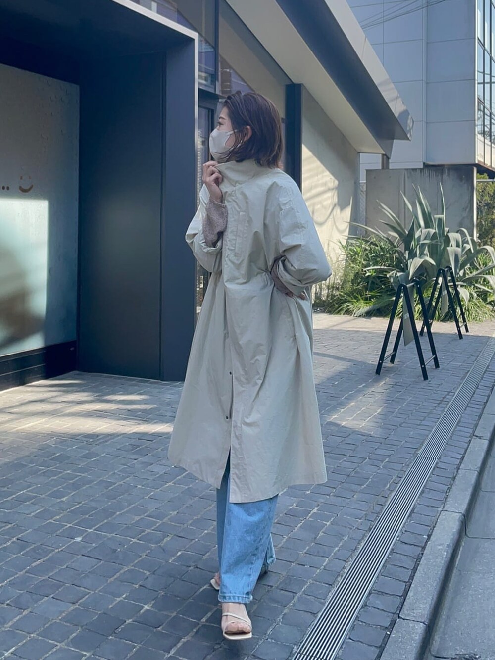 グリーン系のモッズコート、ブラック系のニット/セーター、ブルー系のデニムパンツを着用したレディースの春コーディネートの3枚目の写真