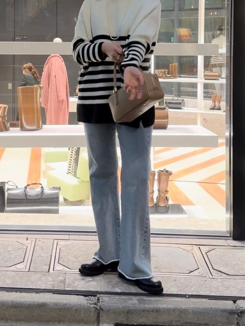 ブルー系のデニムパンツ、イエロー系のボストンバッグ、ブラック系のブーツを着用したレディースの秋コーディネートの4枚目の写真