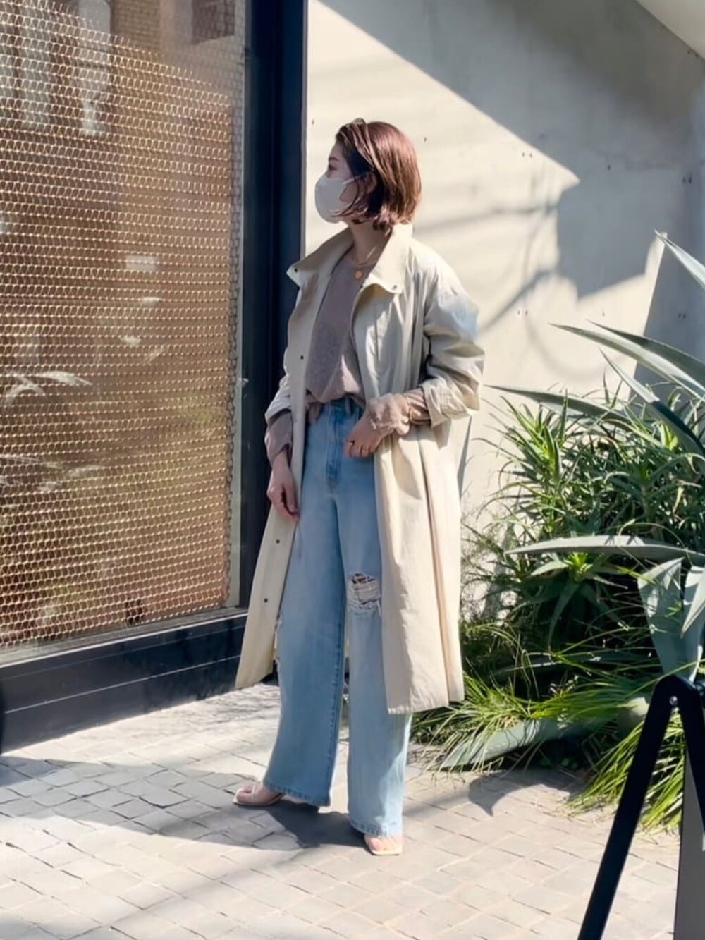 グリーン系のモッズコート、ブラック系のニット/セーター、ブルー系のデニムパンツを着用したレディースの春コーディネートの2枚目の写真