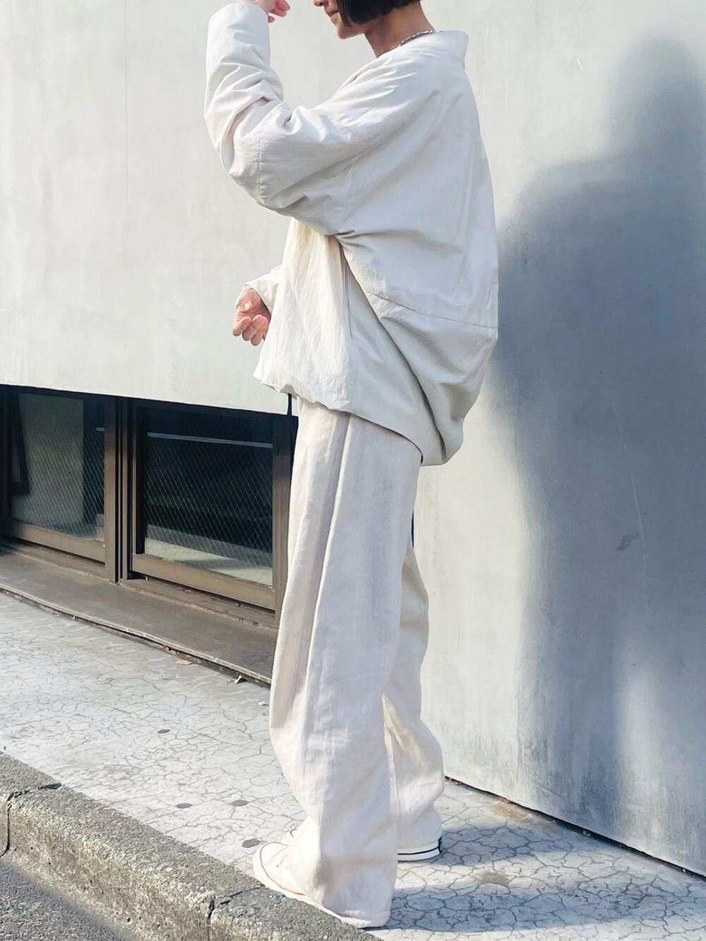 ホワイト系のブルゾン、ピンク系のニット/セーター、ベージュ系のデニムパンツを着用したレディースの春コーディネートの2枚目の写真