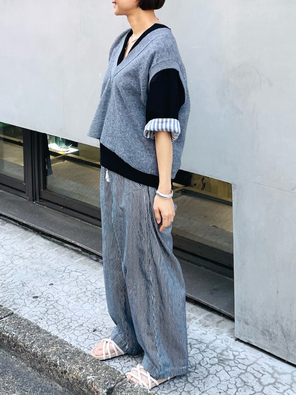 グレー系のベスト、ブラック系のTシャツ/カットソー、ブルー系のデニムパンツを着用したレディースの夏コーディネートの2枚目の写真