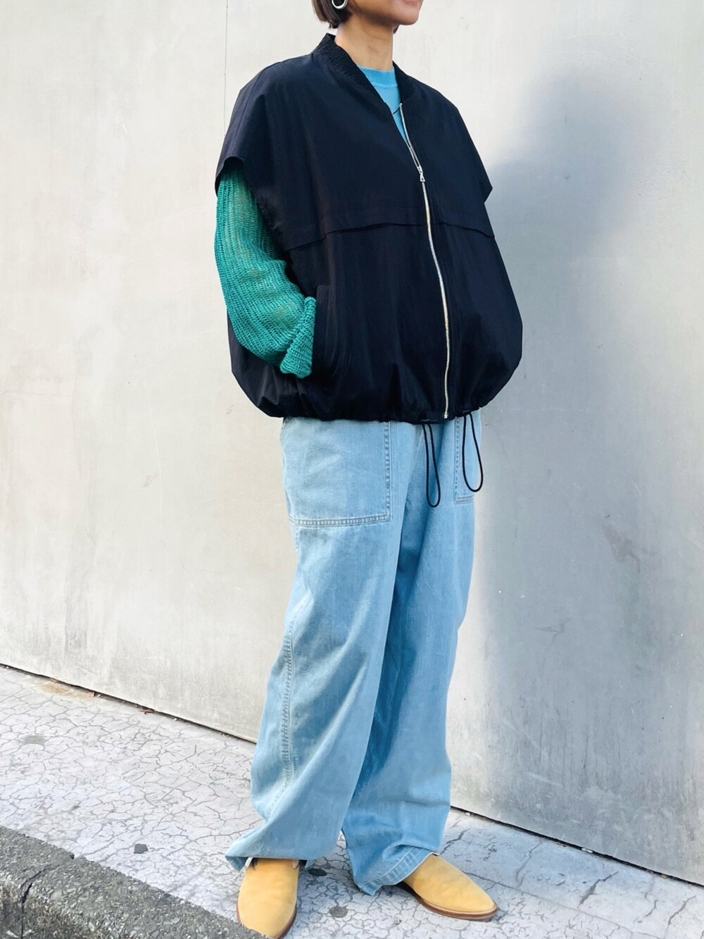 ブラック系のブルゾン、グリーン系のカーディガン/ボレロ、ブルー系のサロペット/オーバーオールを着用したレディースの春コーディネートの2枚目の写真