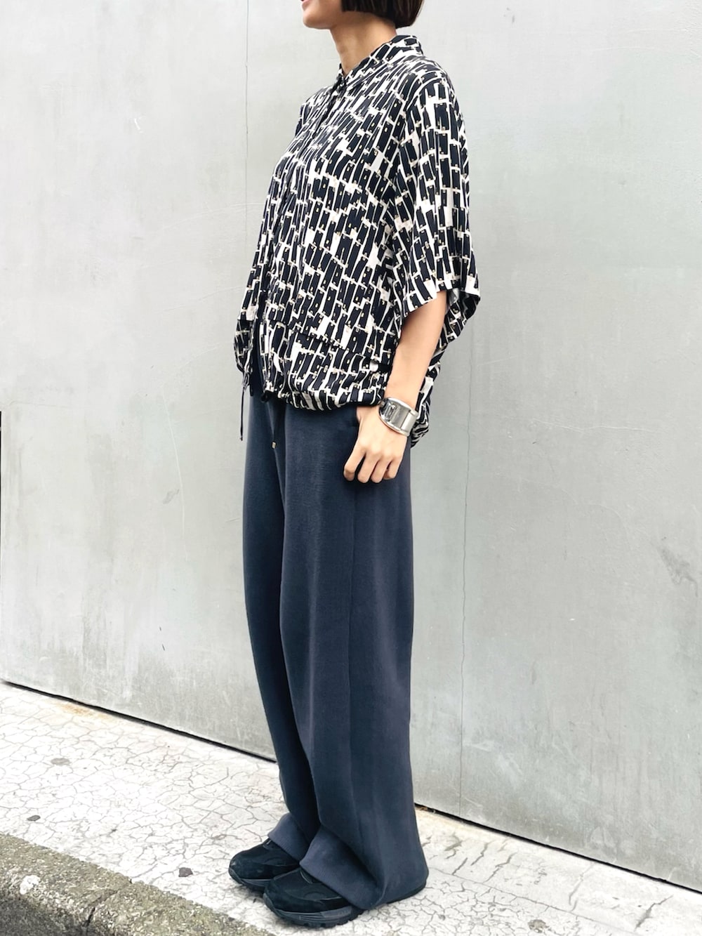 グレー系のその他パンツ、ブラック系のシャツ/ブラウス、ブラック系のスニーカーを着用したレディースの春コーディネートの2枚目の写真