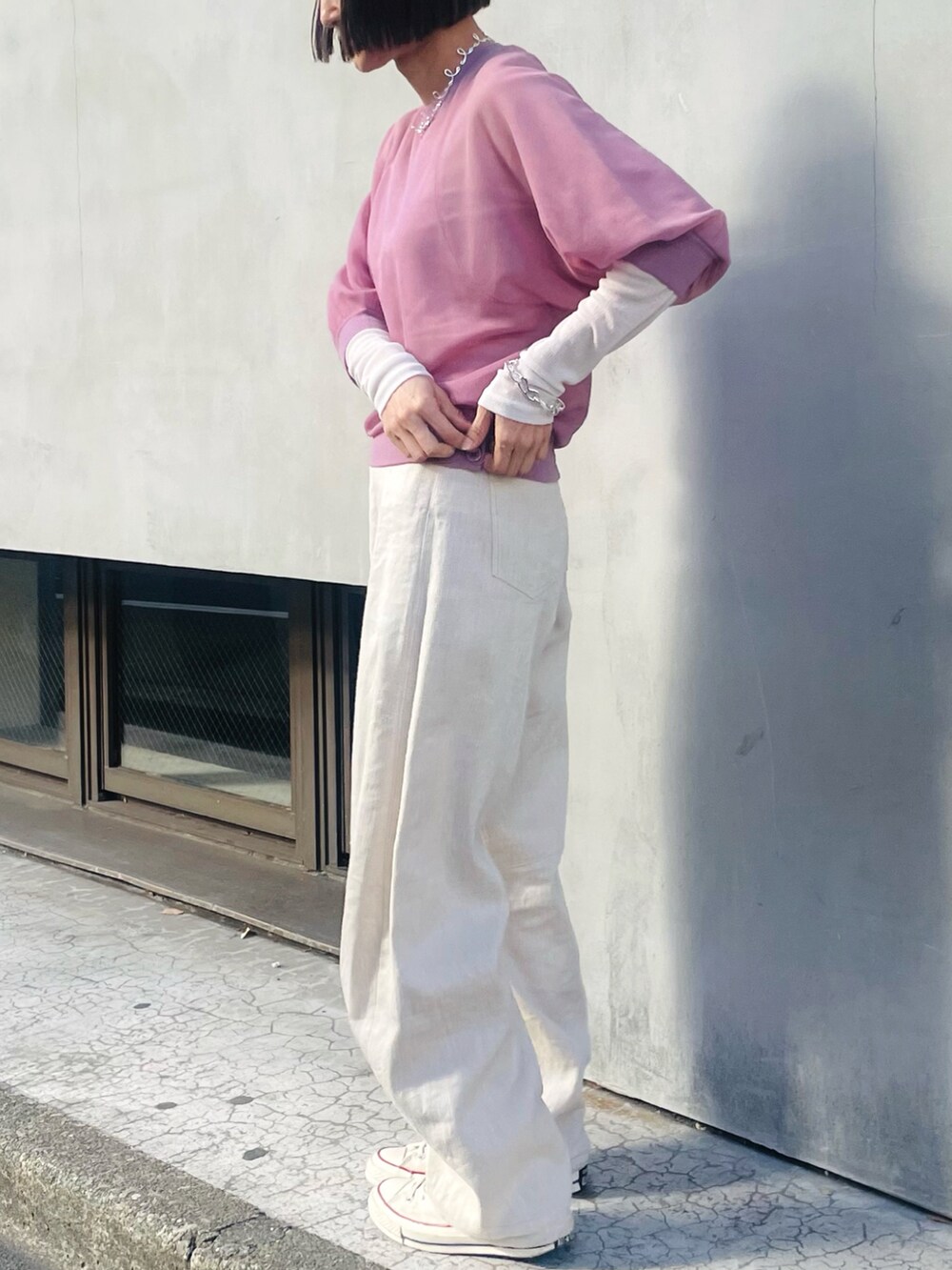 ピンク系のニット/セーター、ベージュ系のデニムパンツ、ホワイト系のTシャツ/カットソーを着用したレディースの春コーディネートの2枚目の写真