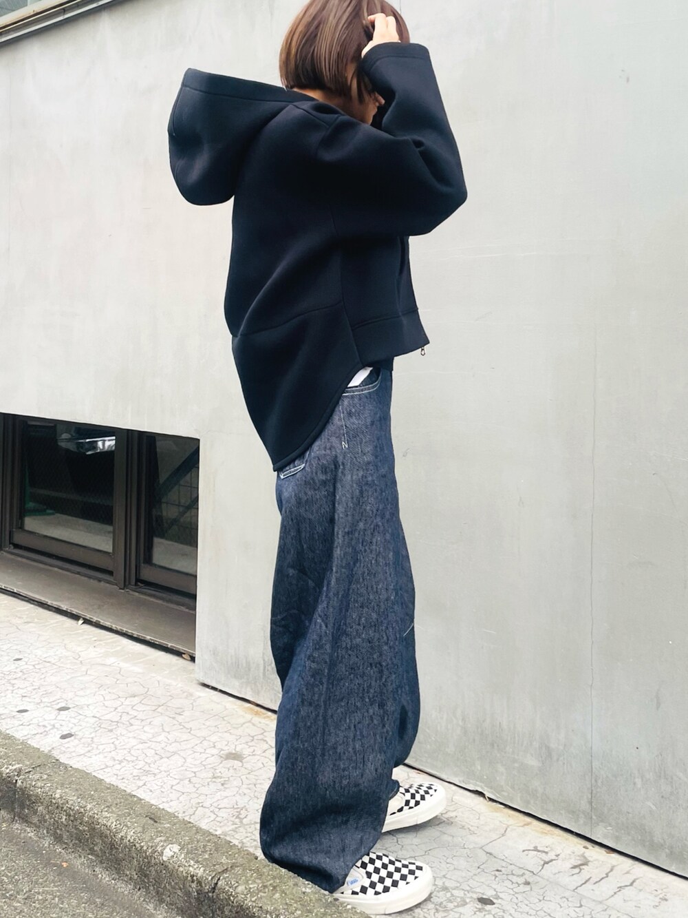 グレー系のパーカー、ブルー系のデニムパンツ、ホワイト系のスニーカーを着用したレディースの冬コーディネートの2枚目の写真