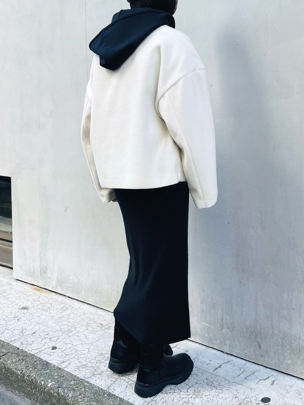 ホワイト系のブルゾン、ブラック系のスカート、ブラック系のパーカーを着用したレディースの冬コーディネートの2枚目の写真