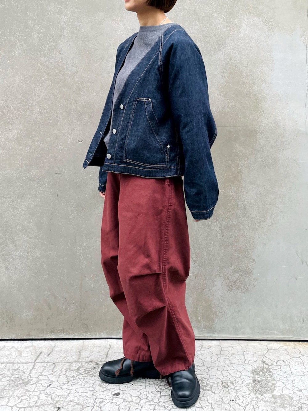 ブラック系のブーツ、ブルー系のデニムジャケット、レッド系のその他パンツを着用したレディースの春コーディネートの2枚目の写真