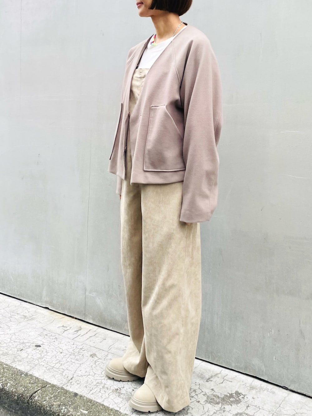 ブラウン系のノーカラージャケット、ベージュ系のサロペット/オーバーオール、ホワイト系のニット/セーターを着用したレディースの秋コーディネートの2枚目の写真