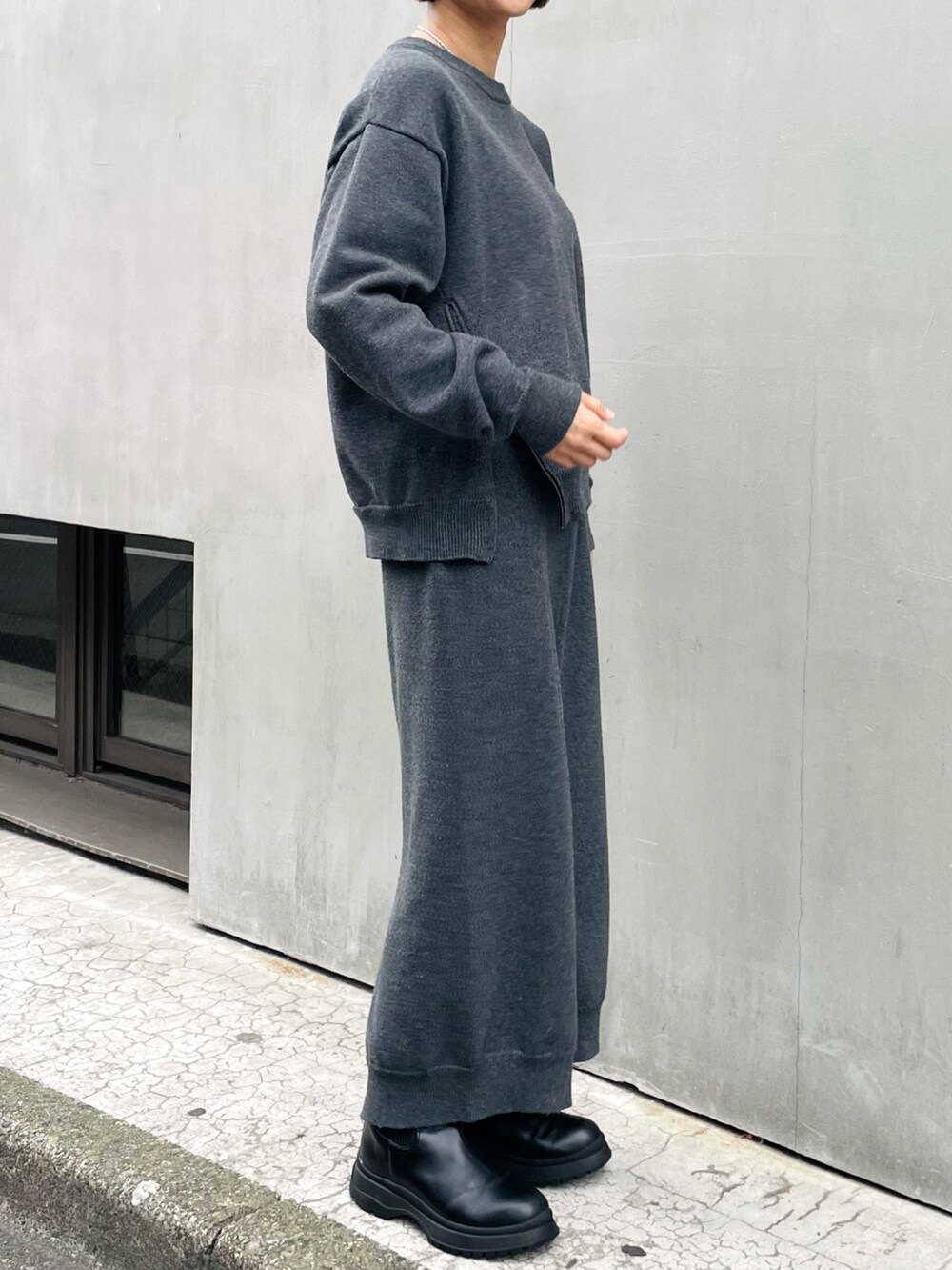 ブラック系のニット/セーター、グレー系のその他パンツ、ブラック系のブーツを着用したレディースの秋コーディネートの2枚目の写真