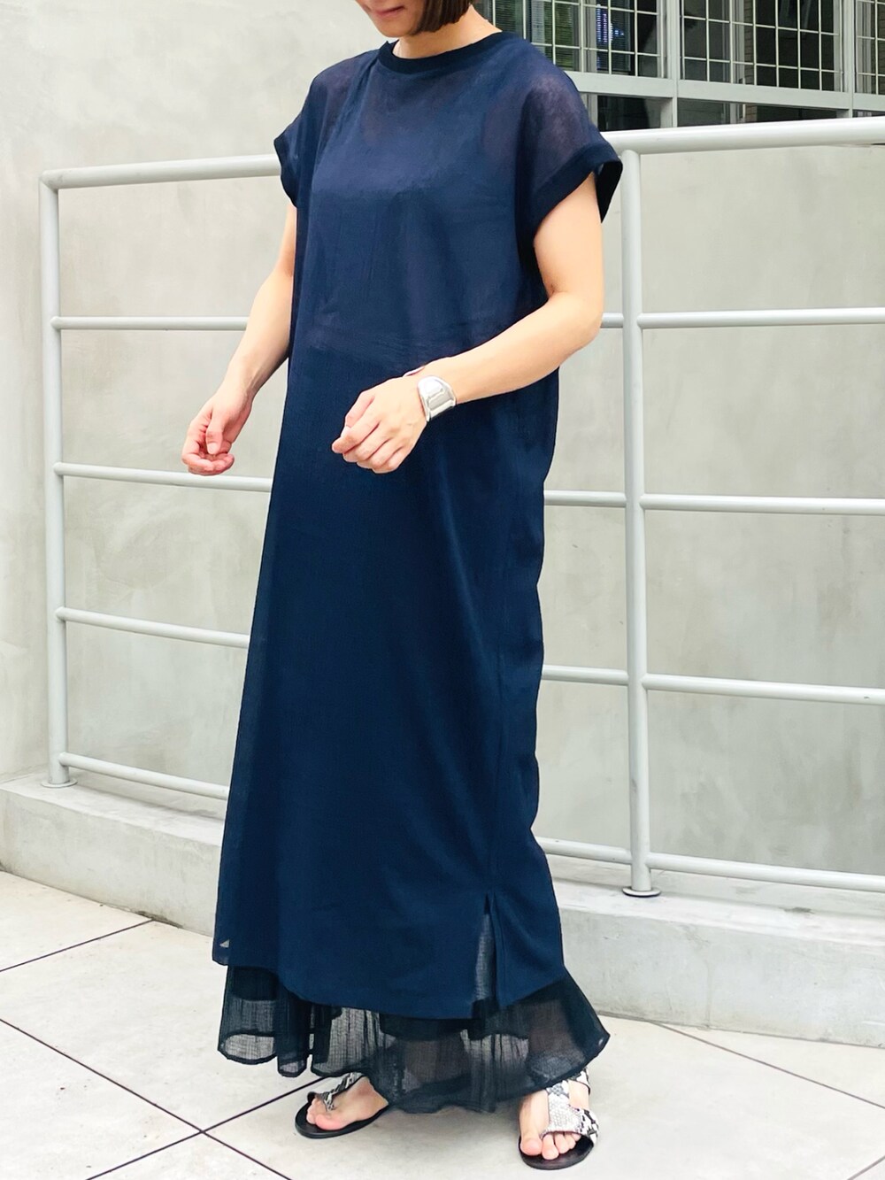 ブルー系のワンピース、ブラック系のスカートを着用したレディースの春コーディネートの2枚目の写真