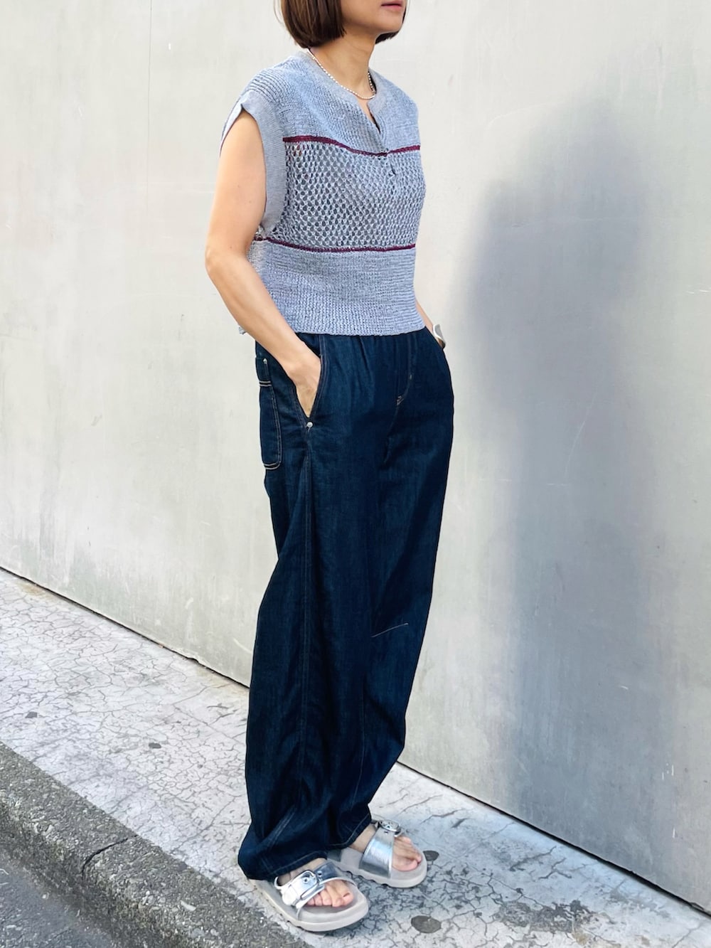 グレー系のニット/セーター、ブルー系のデニムパンツ、シルバー系のサンダルを着用したレディースの夏コーディネートの2枚目の写真