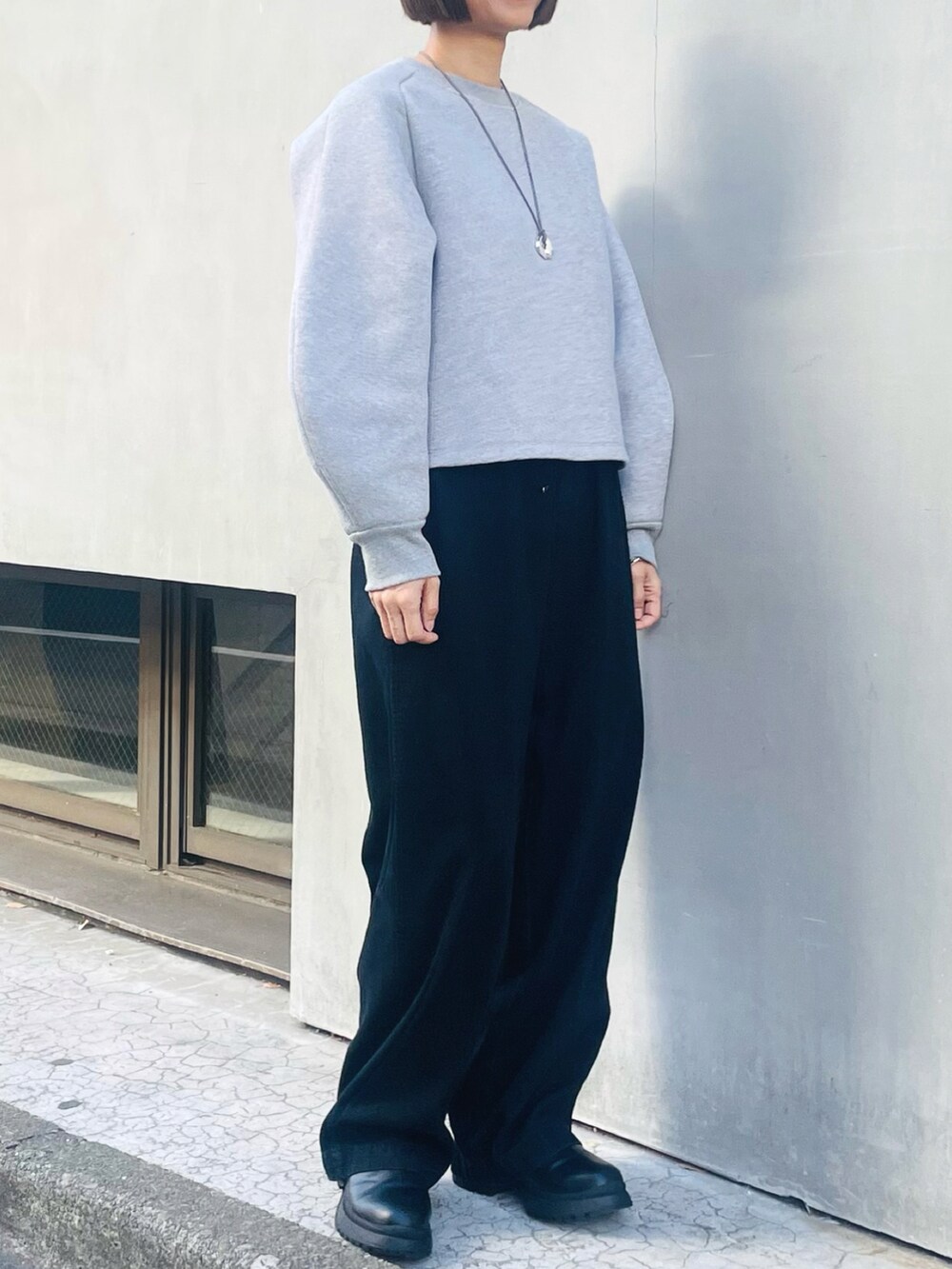 グレー系のスウェット、ブラック系のデニムパンツ、ブラック系のブーツを着用したレディースの冬コーディネートの2枚目の写真