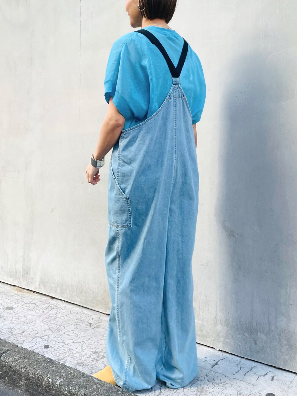 ブルー系のサロペット/オーバーオール、ブルー系のニット/セーター、ベージュ系のサンダルを着用したレディースの春コーディネートの2枚目の写真