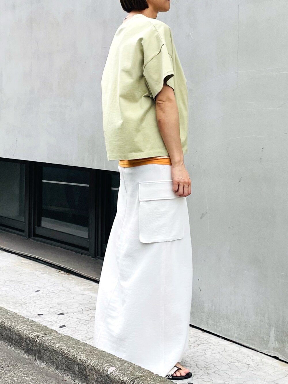 グリーン系のTシャツ/カットソー、ホワイト系のスカート、オレンジ系のタンクトップを着用したレディースの夏コーディネートの2枚目の写真