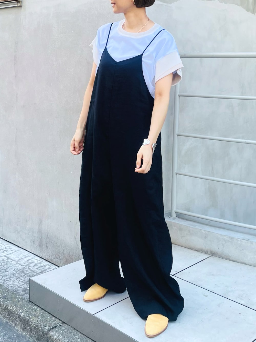 ブラック系のサロペット/オーバーオール、ホワイト系のTシャツ/カットソー、ベージュ系のサンダルを着用したレディースの夏コーディネートの2枚目の写真