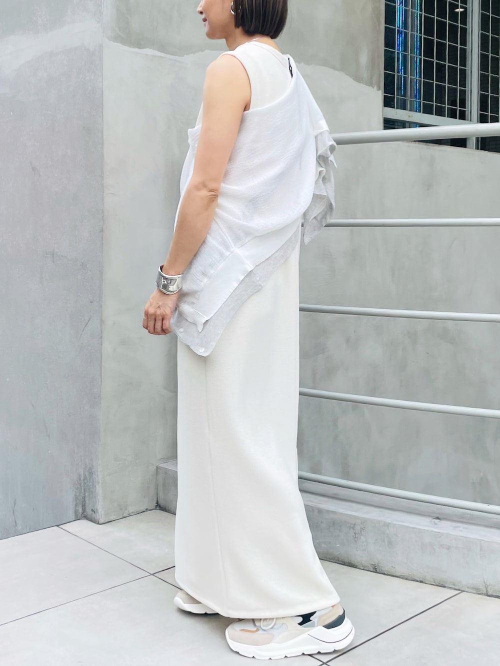 ホワイト系のワンピース、ホワイト系のカーディガン/ボレロ、ベージュ系のスニーカーを着用したレディースの夏コーディネートの2枚目の写真