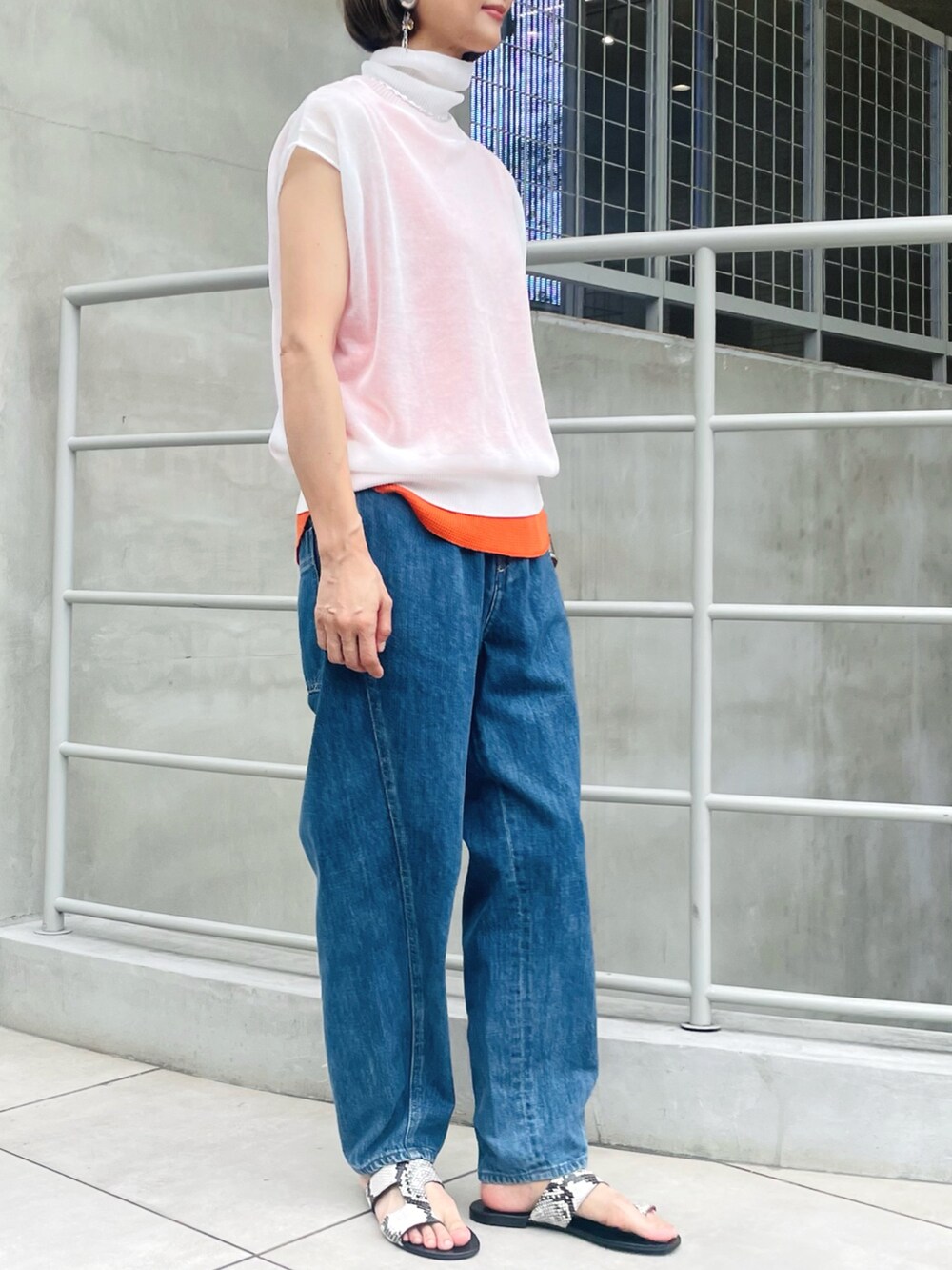 ホワイト系のニット/セーター、ブルー系のデニムパンツ、オレンジ系のタンクトップを着用したレディースの秋コーディネートの2枚目の写真