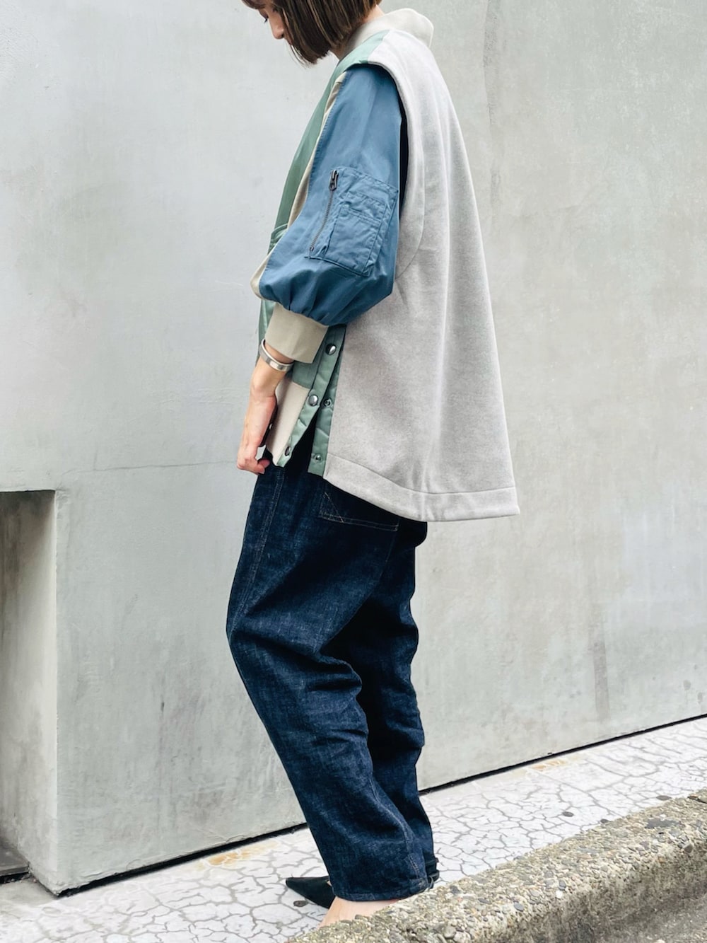 グリーン系のベスト、ブルー系のデニムパンツ、グリーン系のTシャツ/カットソーを着用したレディースの秋コーディネートの2枚目の写真