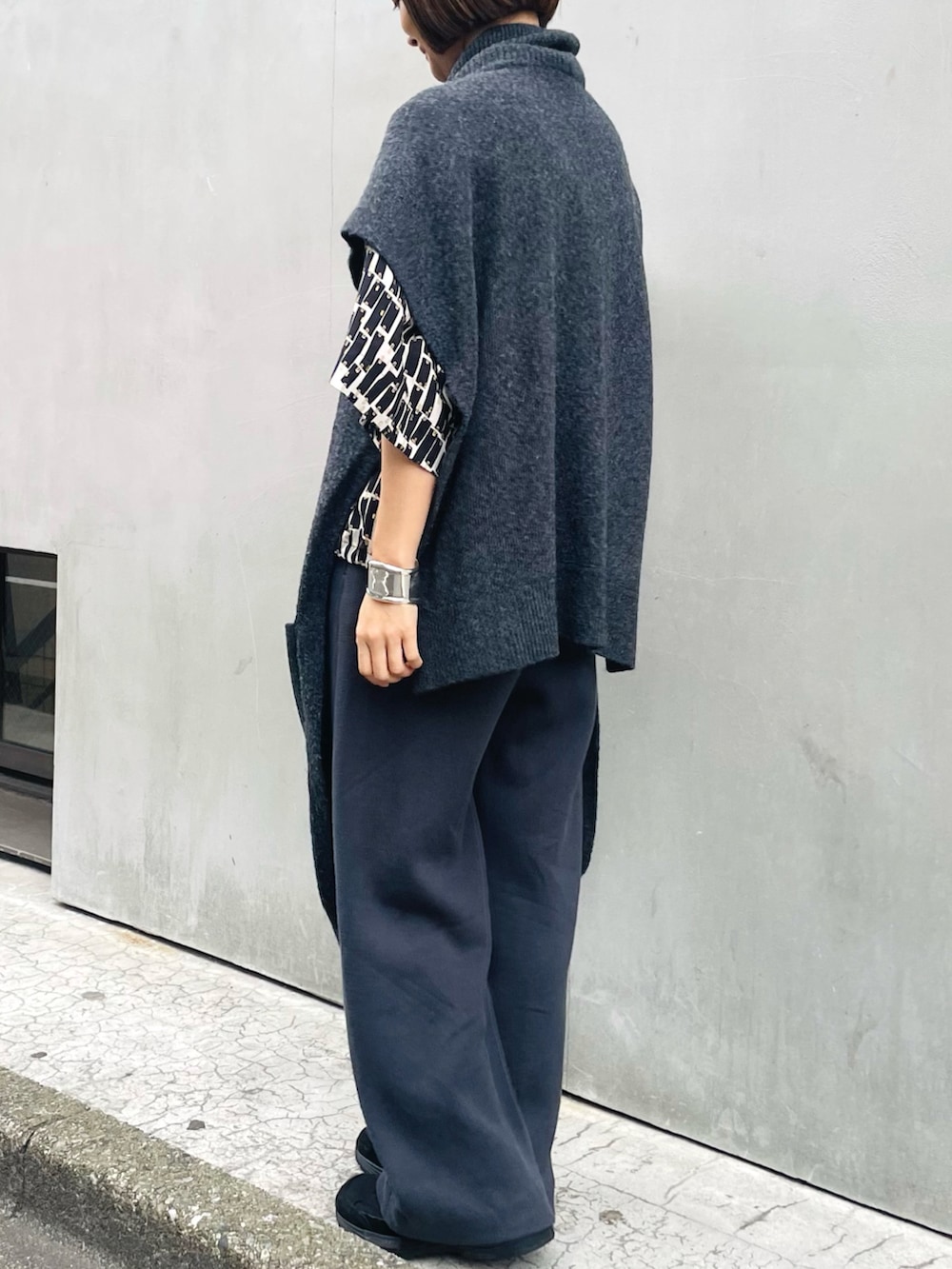 グレー系のニット/セーター、グレー系のその他パンツ、ブラック系のシャツ/ブラウスを着用したレディースの春コーディネートの2枚目の写真