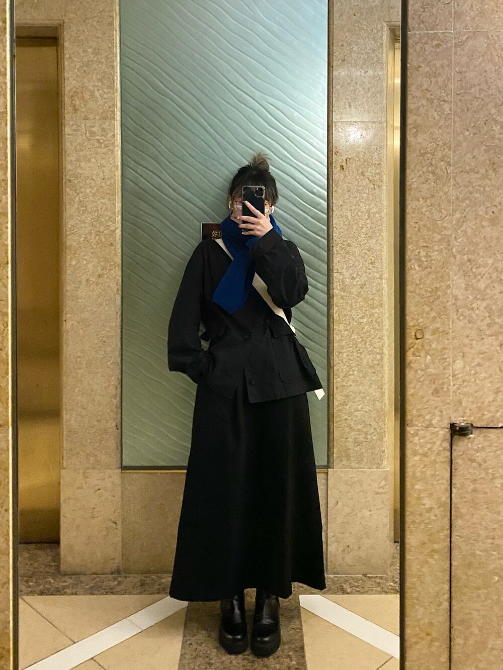 グリーン系のテーラードジャケット、ブラック系のスカートを着用したレディースの冬コーディネートの2枚目の写真