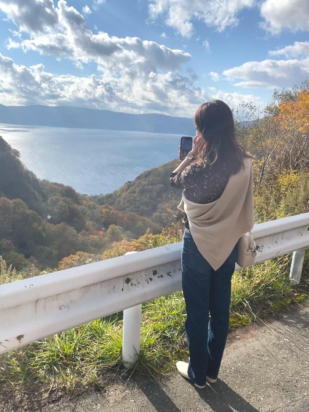 ホワイト系のニット/セーター、ホワイト系のショルダーバッグ、ブルー系のデニムパンツを着用したレディースの秋コーディネートの2枚目の写真