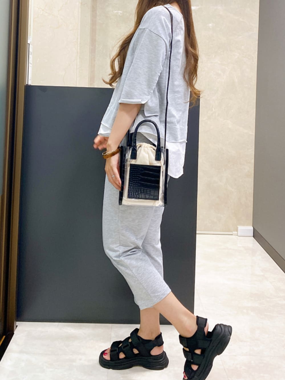 ブラック系のサンダル、グレー系のセットアップ、ブラック系のショルダーバッグを着用したレディースの夏コーディネートの2枚目の写真