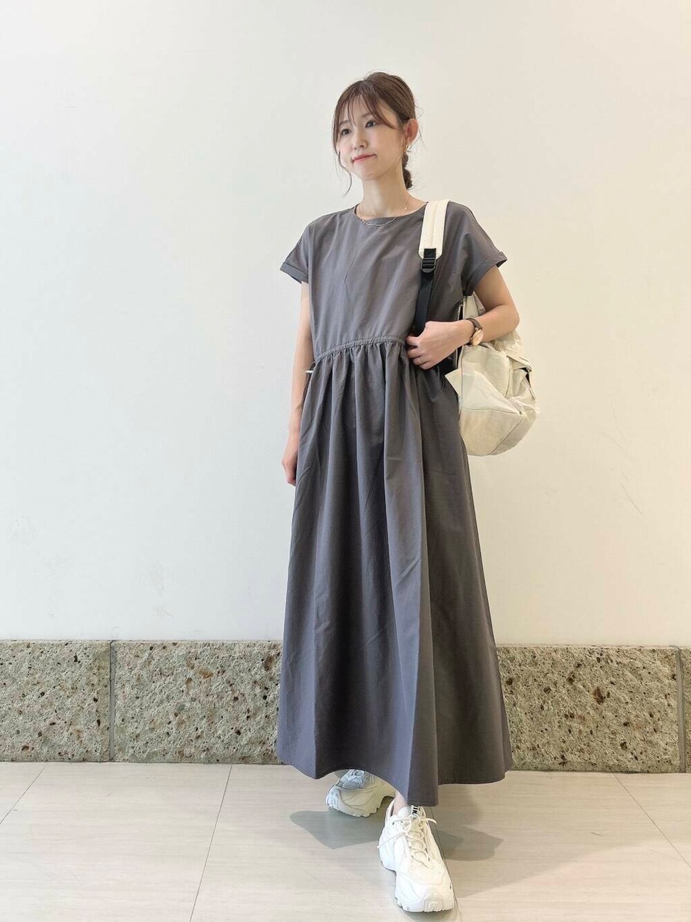 ホワイト系のバックパック/リュック、ホワイト系のスニーカー、グレー系のワンピースを着用したレディースの夏コーディネートの6枚目の写真